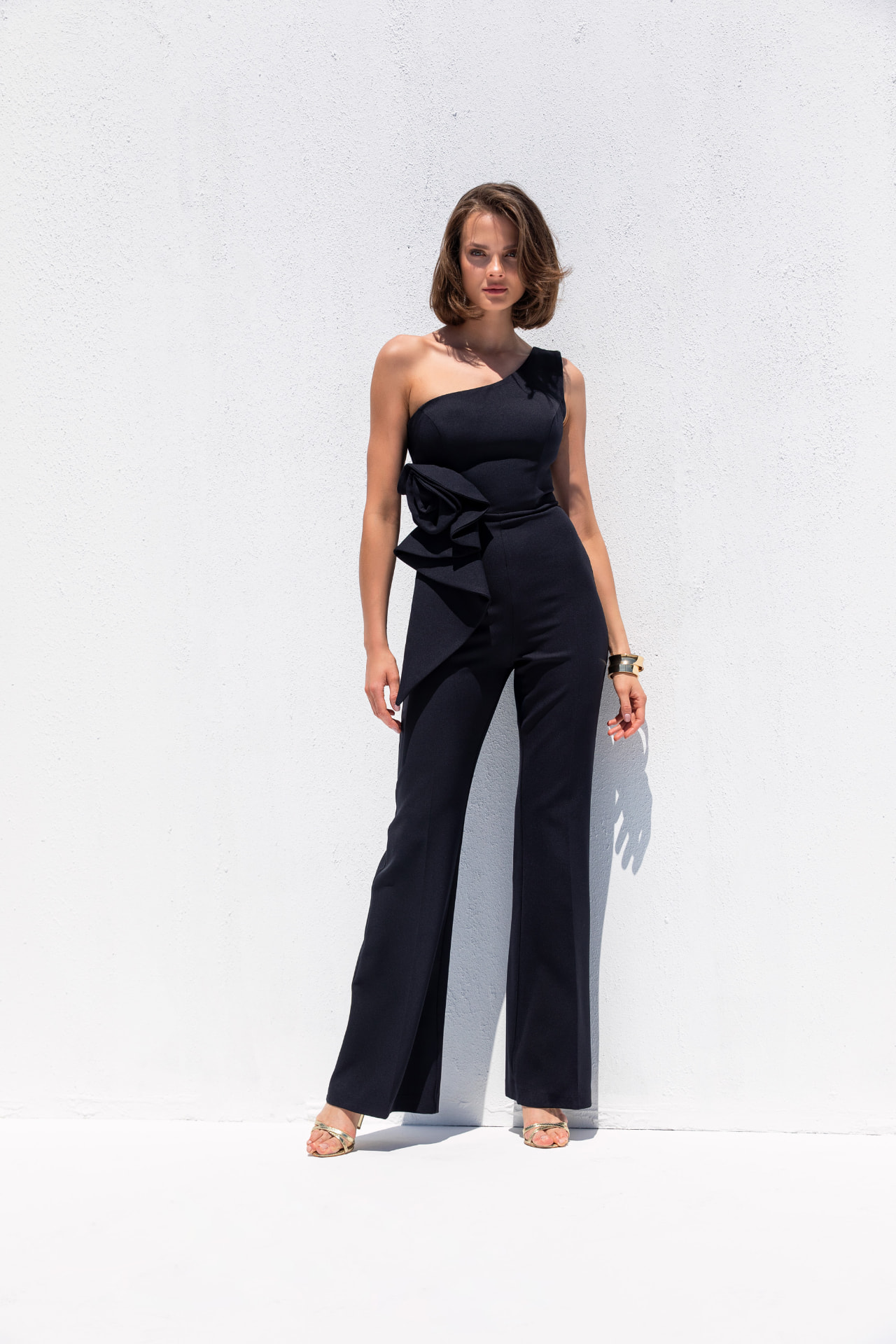 Black one-shoulder crepe jumpsuit with oversized rose waist detail