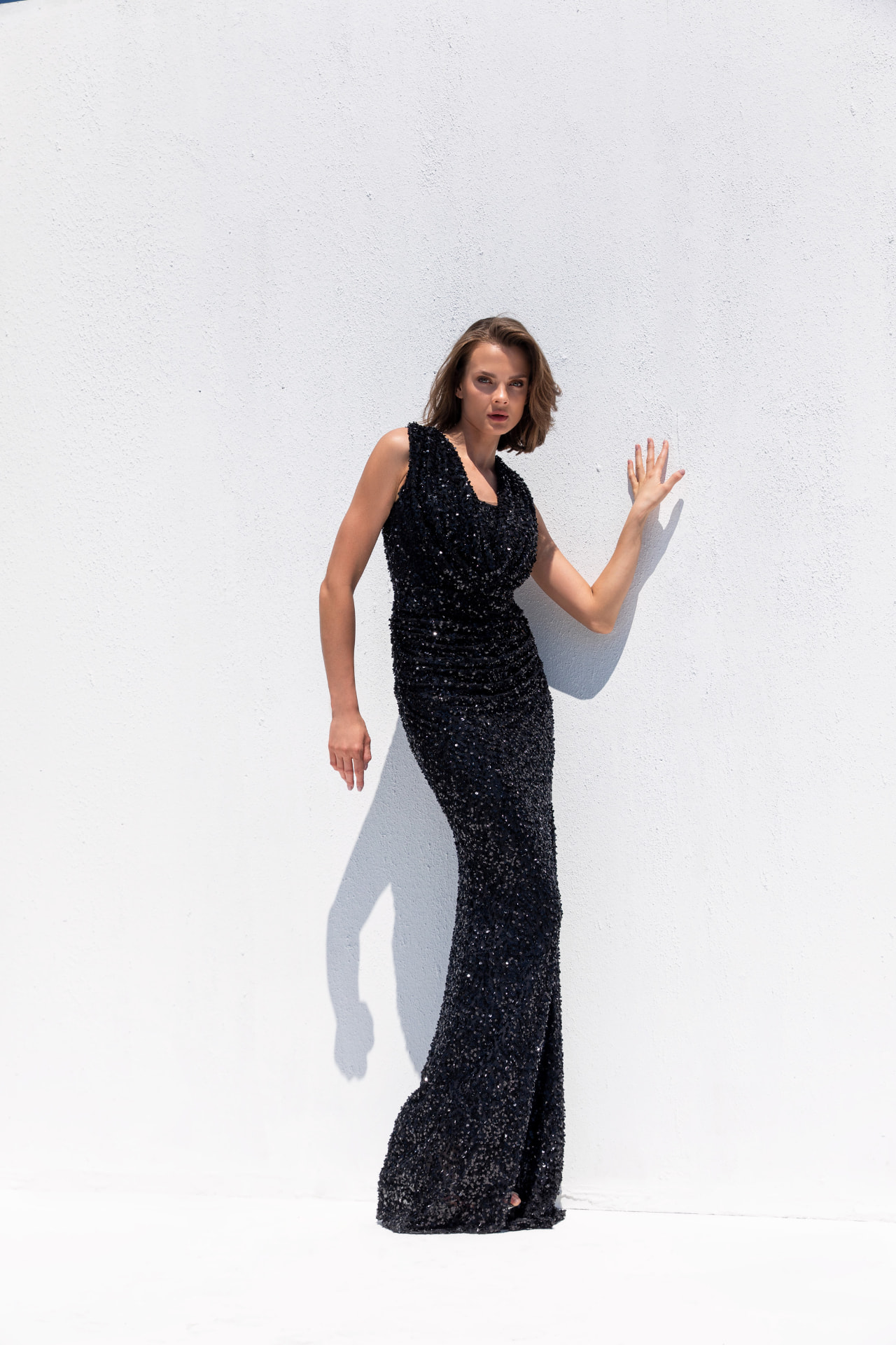 Black sequin sleeveless column gown with cowl neckline and ruched waist